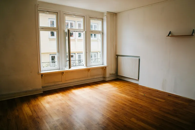 Lege kamer met houten vloer en grote ramen na een ontruiming